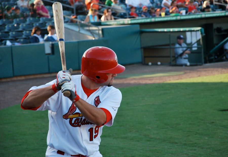 A baseball player with red helmet swinging his bat