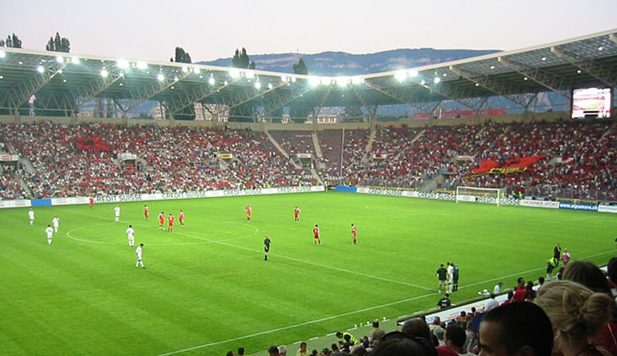 Green football field with full of spectators in the stands.