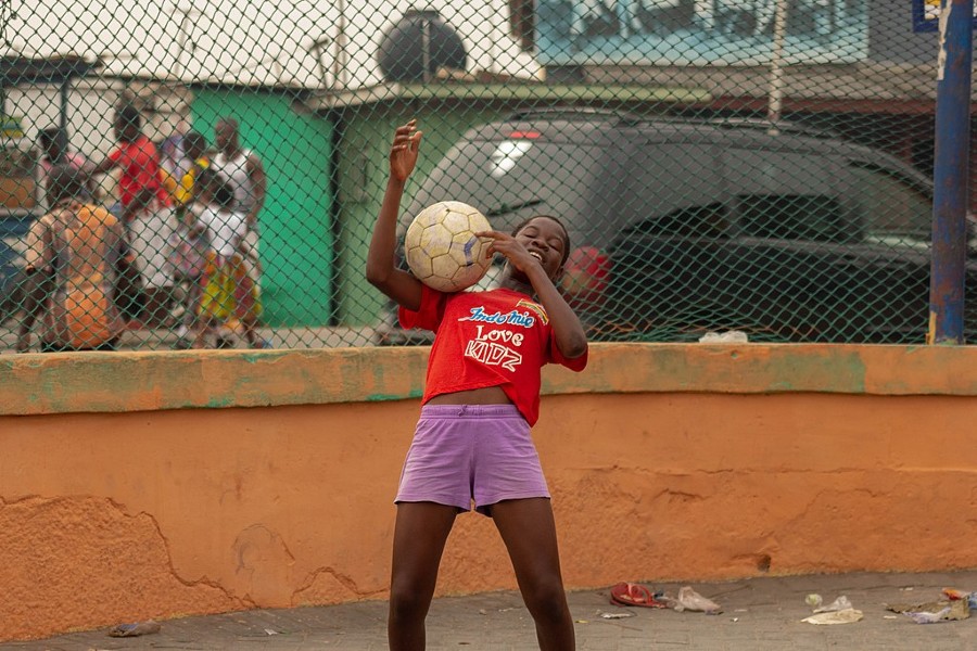 An African girl in red t-shirt practicing her trapping skills in soccer.