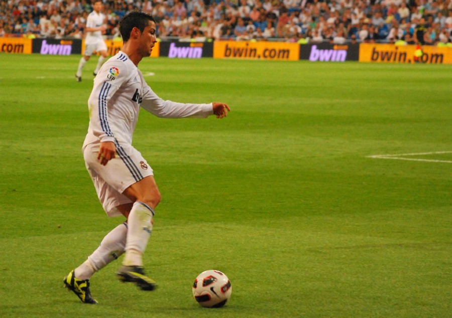 Cristiano Ronaldo in Real Madrid jersey running with the ball.