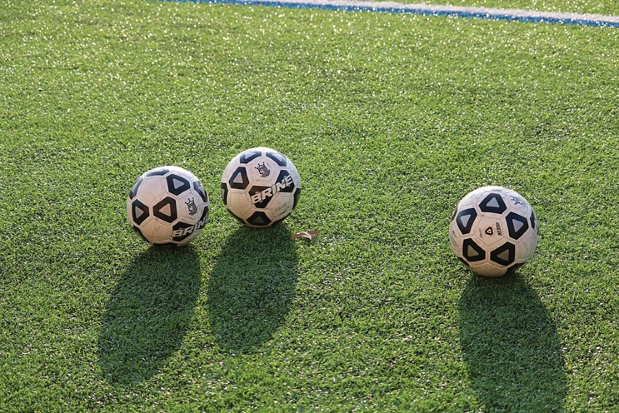 Three "Brine" soccer balls in a green field.